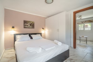 Ein ordentlich bezogenes Bett mit weißen Leinen und Handtüchern, einem Kopfteil und einem Gemälde an der Wand.