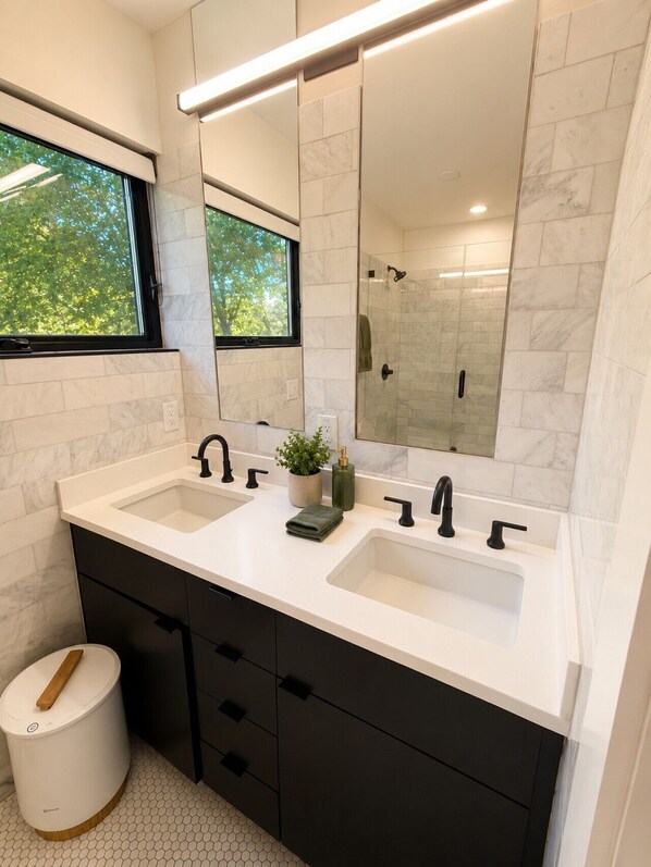 Une salle de bain moderne avec deux lavabos, un grand miroir et une fenêtre.