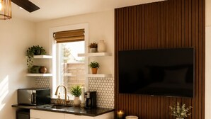 Una cocina moderna con televisor integrado, panel de madera y un rincón de estar acogedor con una manta.