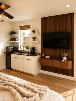 Eine moderne Küche mit integriertem Fernseher, einer Wandverkleidung aus Holzpaneelen und einer gemütlichen Sitzecke mit Decke.