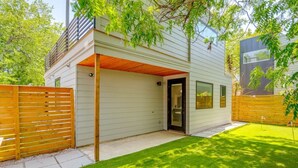Una casa moderna con garaje cubierto, patio cercado y césped cuidado.
