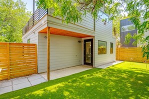Ein modernes Haus mit überdachter Garage, umzäunter Garten und gepflegtem Rasen.