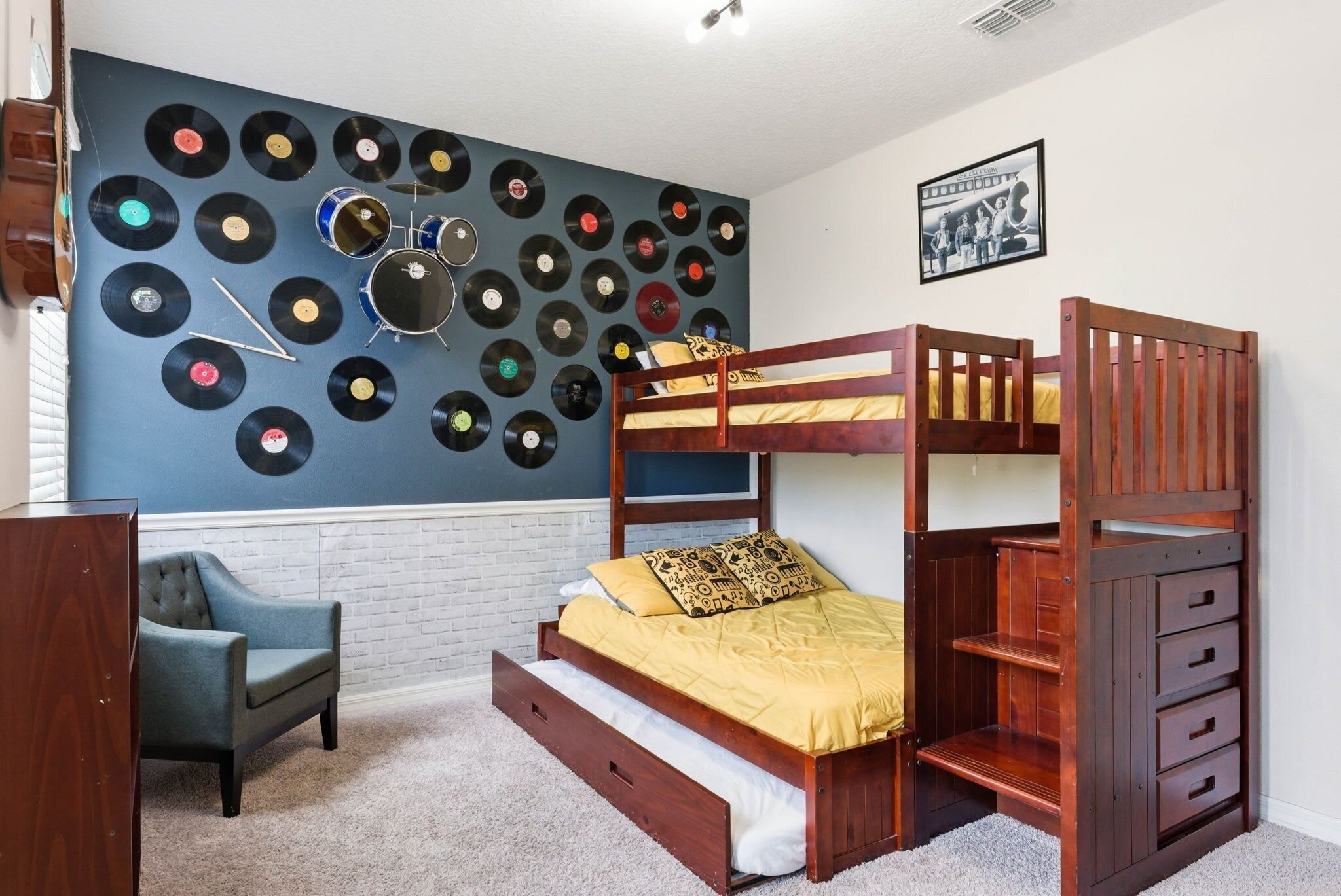 A bunk bed with a record wall, a chair, and a picture on the wall.