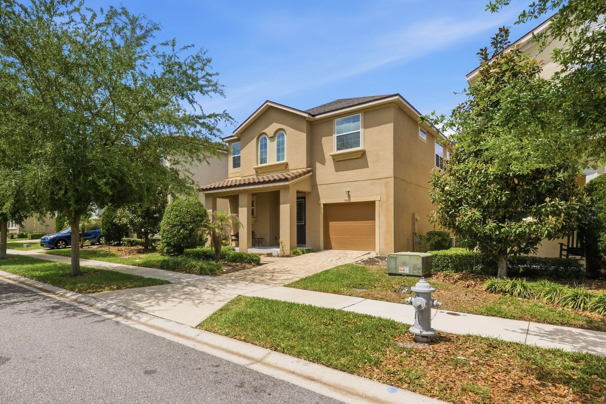 A residential house with a front porch, a garage, and a well-maintained lawn.