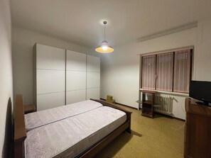 Una camera da letto con un letto, un armadio, un termosifone e una televisione.