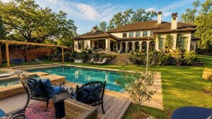 A pool with outdoor seating, a covered patio, and a large house with a garden. - Grand Luxury 11,000 sq ft Estate — 6BR, 8BA, Pool & Premium Finishes (Dallas)
