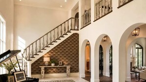 A grand foyer with a piano, a staircase, and a fireplace. - Grand Luxury 11,000 sq ft Estate — 6BR, 8BA, Pool & Premium Finishes (Dallas)