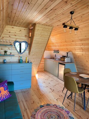 A cozy cabin interior with a loft bedroom, a kitchen, and a dining area.