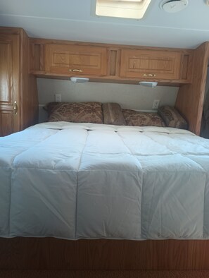 Ein Schlafzimmer mit Bett, Holzschränken und einem Dachfenster.