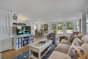 Ampla sala de estar com televisão, assentos e vista para o exterior.