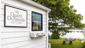 Una cabaña blanca con un letrero que dice 'The Quaint Oceanside Cottage'.