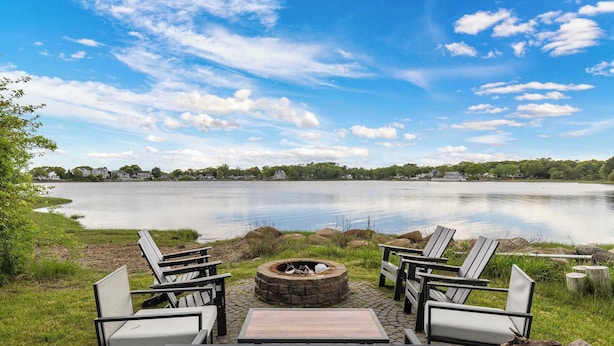 Un espacio de descanso junto al lago con sillas Adirondack, una chimenea y vistas a un lago tranquilo.