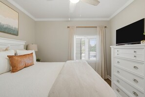 Ein Schlafzimmer mit einem Bett, einem Schminktisch, einem Fernseher und einem Fenster mit Vorhängen.