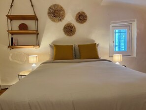 Une chambre à coucher avec un lit, deux lampes de chevet, une fenêtre et des éléments de décoration murale.