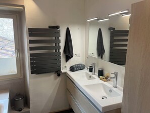 Een moderne badkamer met een grote spiegel, een handdoekrek, een wastafel en een toilet.