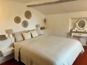 Une chambre à coucher comprenant un lit, des tables de chevet, des éléments de décoration murale et une commode avec un miroir.