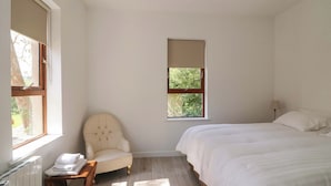 Una camera da letto con un letto, una sedia, una finestra e un termosifone.