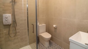Un bagno con cabina doccia in vetro, un water e un lavandino.