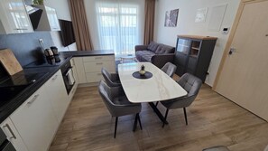 Eine moderne Küche mit Essbereich, ausgestattet mit einem Marmortisch, grauen Stühlen und einem kleinen Topf mit Pflanze.