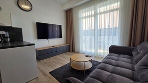 En moderne stue med et fladskærms-tv, en sofa, et sofabord og en skydedør til terrassen.