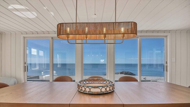 A dining area with a large wooden table, wicker centerpiece, and a hanging light fixture.
