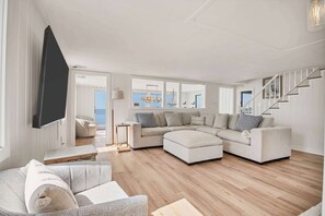 Ein modernes Wohnzimmer mit einem Ecksofa, einem Flachbildfernseher und einer Treppe.