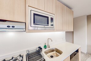 Una cocina moderna con microondas integrado, pileta de acero inoxidable y lavavajillas.