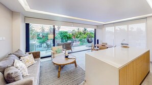 Un salon moderne avec un canapé, une table ronde en bois et un îlot de cuisine.