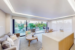 A modern living room with a sofa, a round wooden table, and a kitchen island.