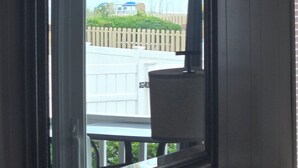 Janela com vista para uma cerca branca e vegetação.