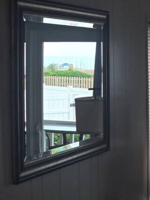 Una ventana con vistas a una cerca blanca y follaje.
