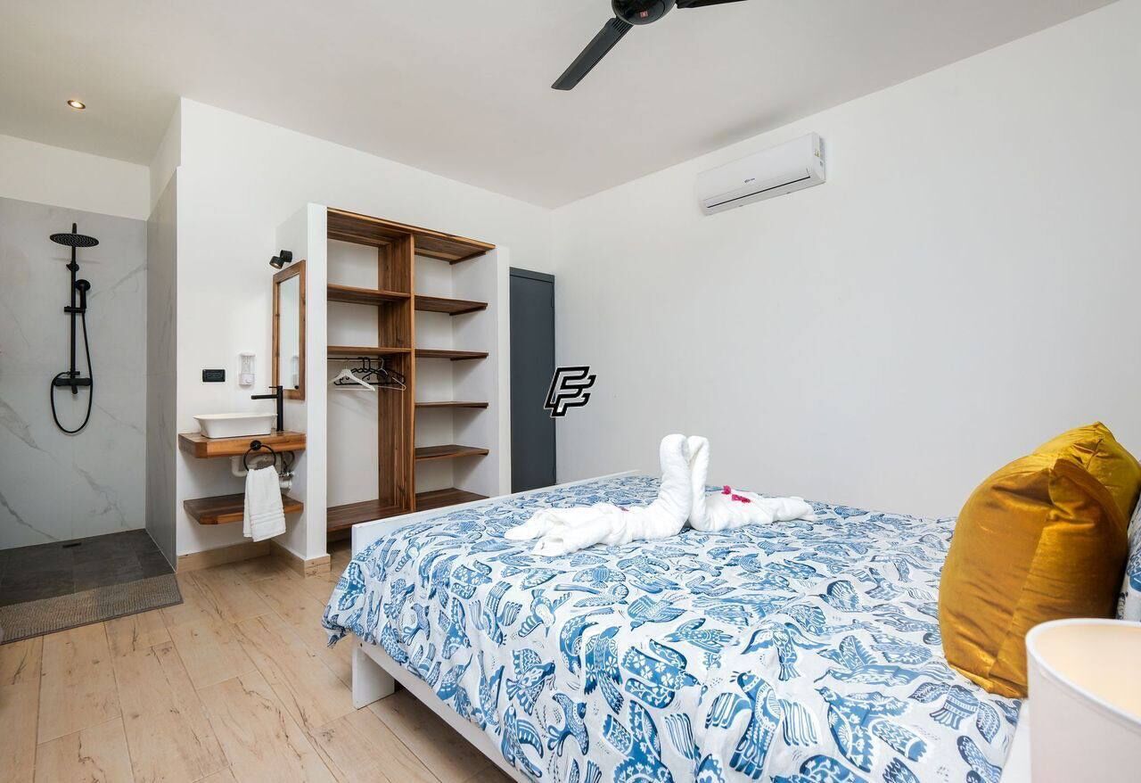 Een moderne slaapkamer met een bed, een inbouwkast, een douchegedeelte en een kleine badkamer.