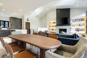 A modern living room with a fireplace, a dining area, and a kitchen with a built-in oven. - Modern Mountain Home with Lux Kitchen & Cozy Living Room Heart of Beaver Creek (Beaver Creek)