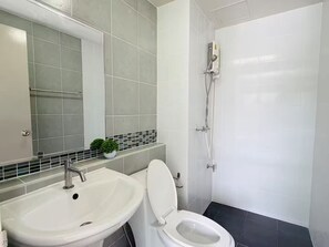 Un baño con lavamanos, inodoro y ducha blancos.