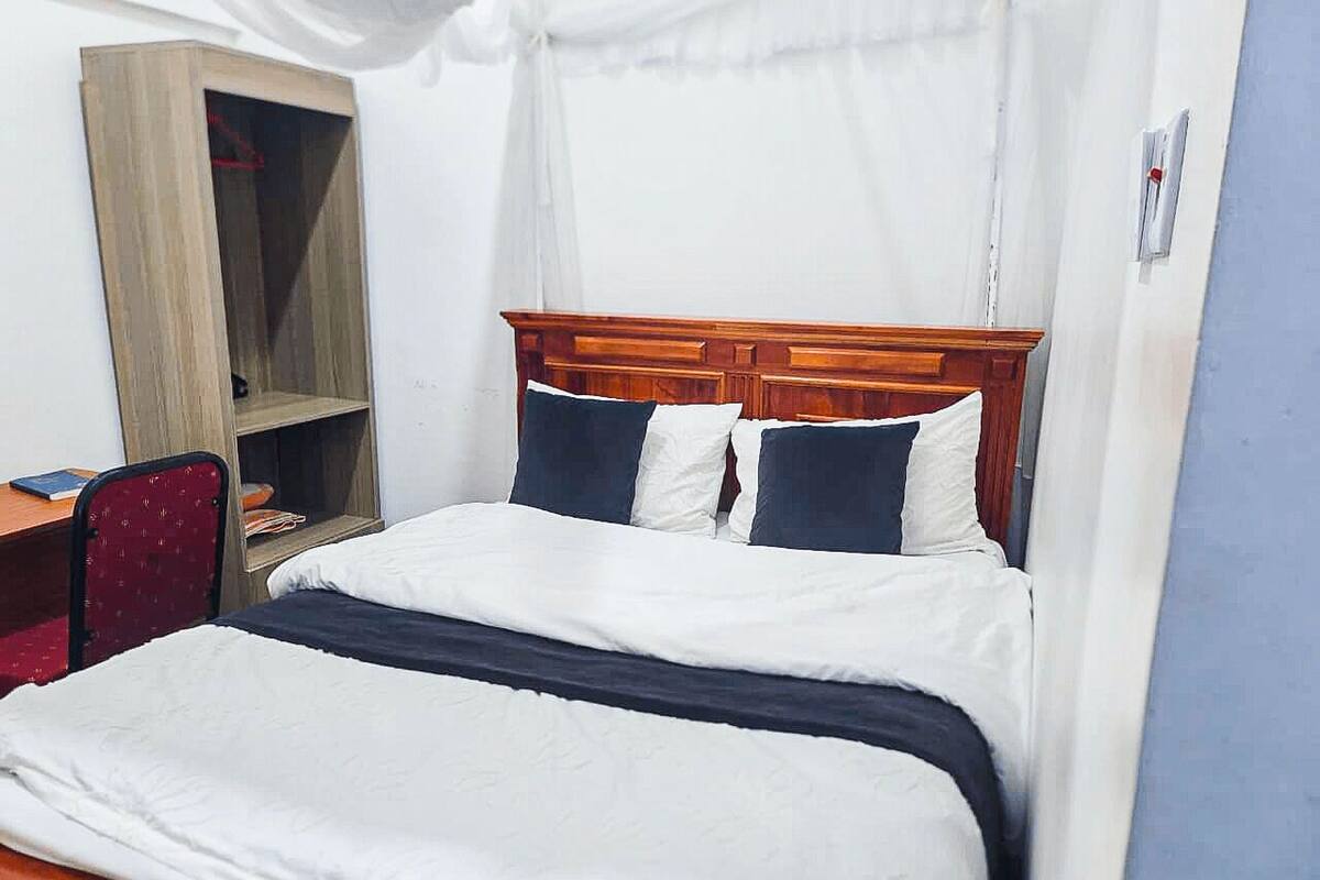 A double bed with a wooden headboard, a bedside table, and a chair.