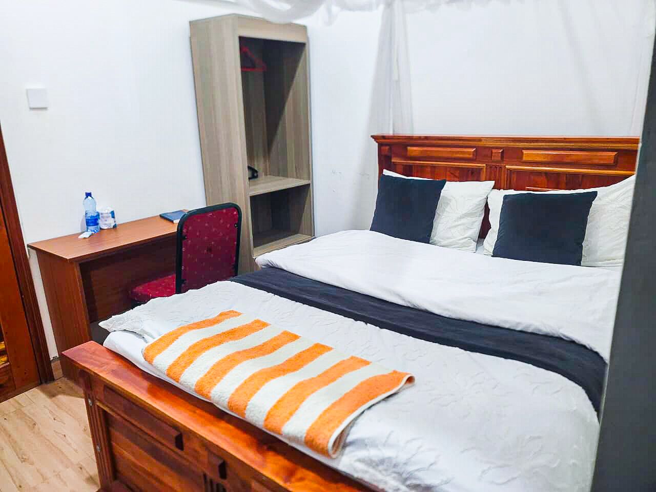 Ett hotellrum med en säng, ett skrivbord, en stol, en garderob och ett fönster.