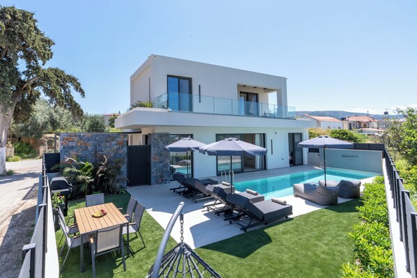 Ein modernes, zweistöckiges Haus mit Swimmingpool, Außenbereich und Blick auf die Umgebung.