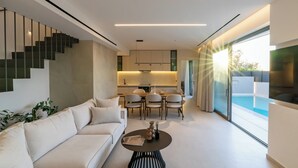 A modern living room with a sofa, dining table, chairs, and a staircase. - Green villas, perfect for relaxing family or friends’ vacations (Rethymno)