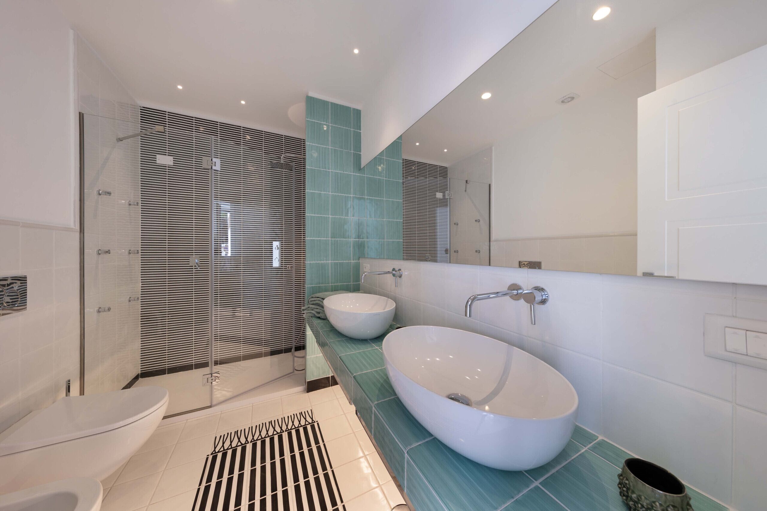 Un baño moderno con cabina de ducha de vidrio, un lavamanos independiente grande y un inodoro.