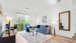 Ein modernes Wohnzimmer mit einer Couch, einem Couchtisch und einem großen Fenster.