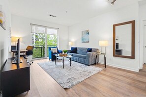 Ein modernes Wohnzimmer mit einer Couch, einem Couchtisch und einem großen Fenster.