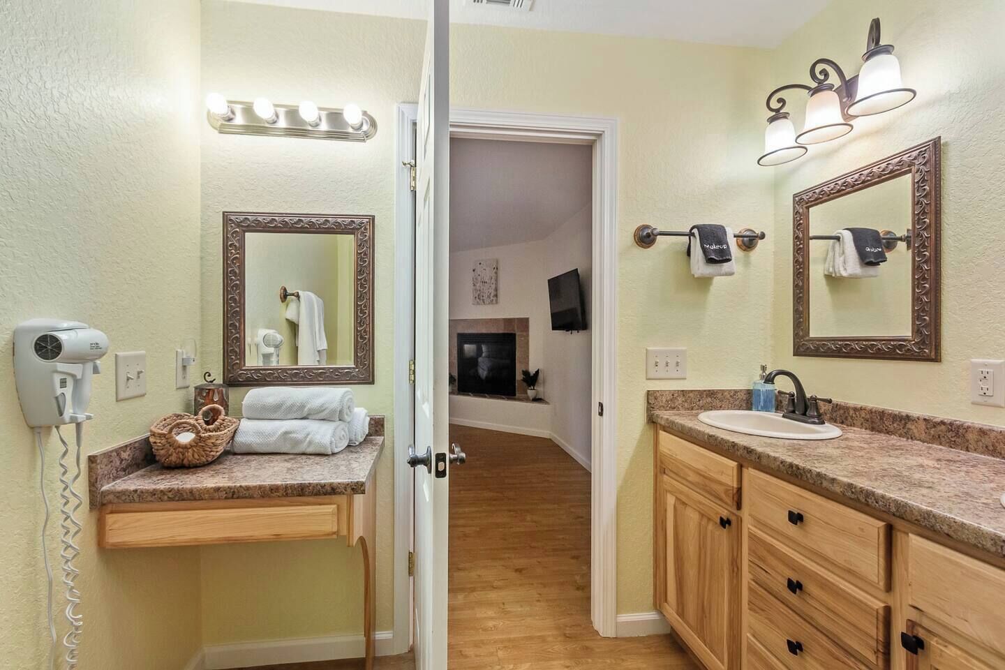 A bathroom with two sinks, vanity mirrors, a hairdryer, and a towel rack.