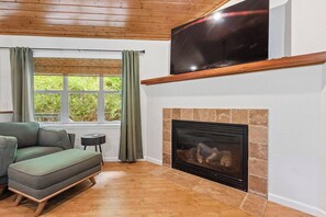 Una sala de estar con sofá, televisor, chimenea y ventana con cortinas.