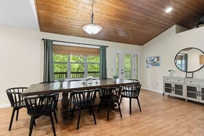 A dining area with a wooden table and chairs, large windows with curtains, a white cabinet, and a ceiling light. - Spacious 4-Bedroom Cabin with Theater, Game Room, Fireplaces & Year-Round Views (Murphy)
