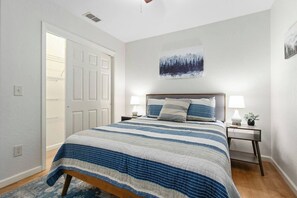 Un dormitorio con una cama, dos mesitas de noche, un aparador y un cuadro colgado en la pared.