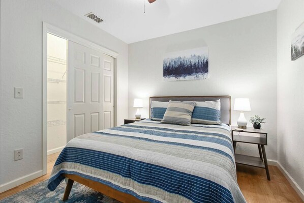 A bedroom with a bed, two bedside tables, a nightstand, a door, and a wall-mounted picture. - Spacious 4-Bedroom Cabin with Theater, Game Room, Fireplaces & Year-Round Views (Murphy)