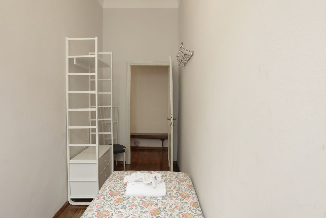A bedroom with a bed, a white wardrobe, and a door leading to a closet.