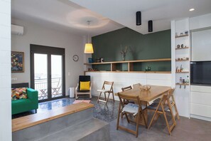 Eine moderne Küche mit Essbereich, einem grünen Sofa und einer Treppe, die auf einen Balkon führt.