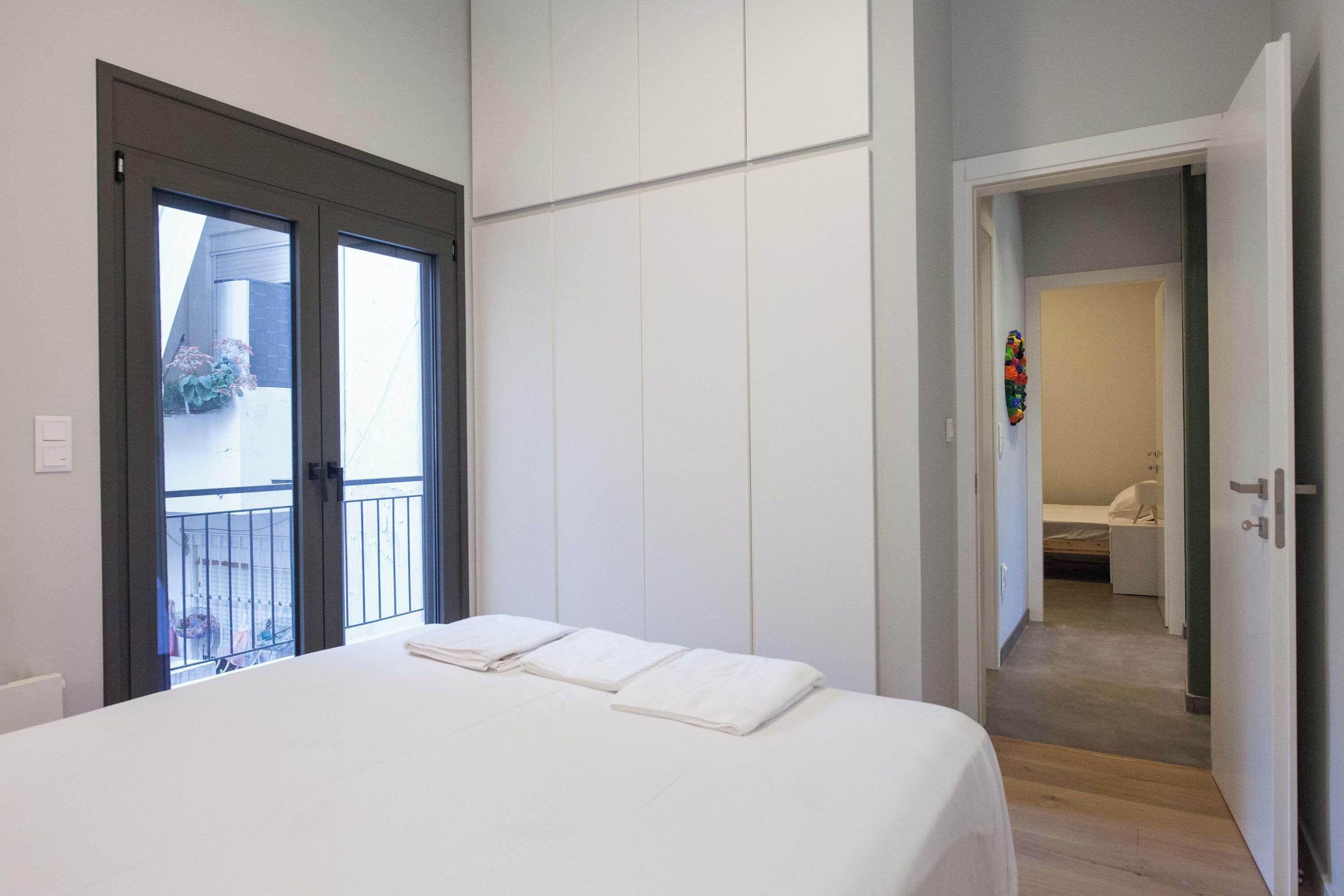 Een slaapkamer met een bed, een balkon en een badkamer, zichtbaar door een open deur.