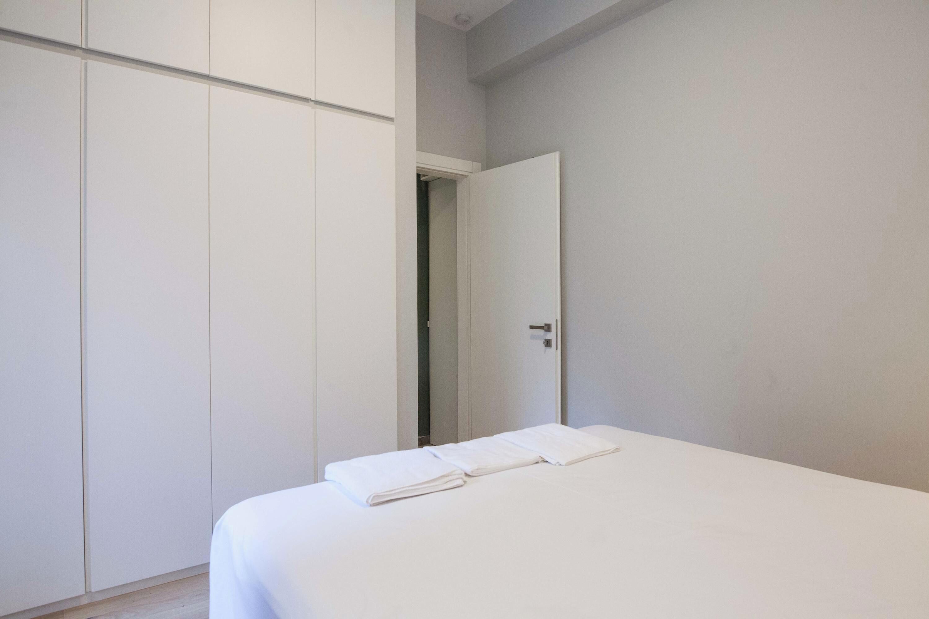 Ein Schlafzimmer mit einem Bett, einem Kleiderschrank und einer Tür zu einem anderen Raum.